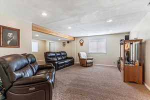 Living area featuring light colored carpet, recessed lighting, and beam ceiling