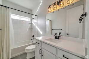 Bathroom featuring shower / tub combo, vanity, and dark tile patterned floors