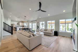 Living area with recessed lighting, light wood finished floors, stairway, a ceiling fan, and vaulted ceiling