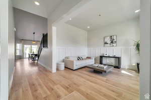 Living area featuring light wood-style floors, a decorative wall, recessed lighting, and a wainscoted wall