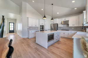 Kitchen with tasteful backsplash, a center island, hanging light fixtures, white cabinetry, and recessed lighting