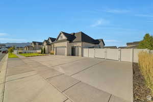View of home's exterior featuring a gate, driveway, an attached garage, and a residential view