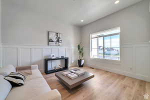 Living area featuring a decorative wall, a wainscoted wall, light wood finished floors, and recessed lighting