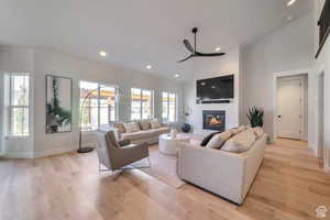 Living room featuring a glass covered fireplace, recessed lighting, light wood-style flooring, and ceiling fan