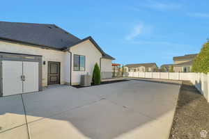 Rear view of house with stone siding, a fenced backyard, stucco siding, a patio area, and concrete driveway