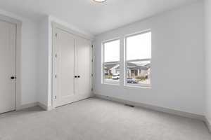 Unfurnished bedroom with light carpet and a closet