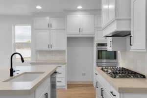Kitchen featuring white cabinets, recessed lighting, stainless steel gas stovetop, decorative backsplash, and light wood-style flooring