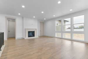 Unfurnished living room with a glass covered fireplace, recessed lighting, and light wood-type flooring