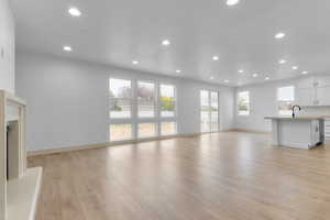 Unfurnished living room featuring light wood finished floors, recessed lighting, and a premium fireplace