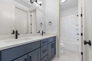 Bathroom featuring double vanity, shower / bath combination, and light tile patterned floors