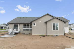 Back of property with stucco siding and a shingled roof