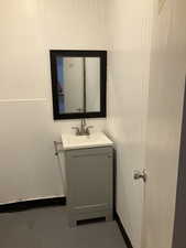 Bathroom with vanity, wooden walls, and concrete floors