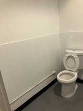 Bathroom featuring a wainscoted wall and finished concrete floors