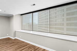 Spare room with wood finished floors and crown molding