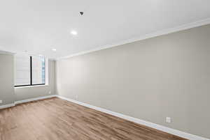 Spare room featuring light wood-type flooring, ornamental molding, and recessed lighting