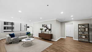 Living area with recessed lighting, wood finished floors, and crown molding