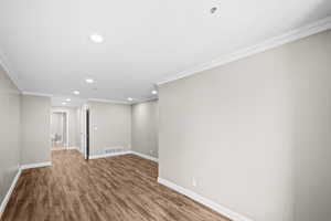 Empty room featuring recessed lighting, crown molding, and wood finished floors