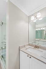 Full bathroom featuring a stall shower, crown molding, and vanity