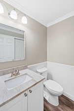 Bathroom with vanity, crown molding, dark wood finished floors, and wainscoting