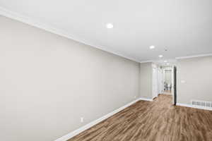 Empty room with crown molding, recessed lighting, and wood finished floors