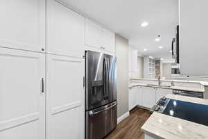 Kitchen featuring stainless steel appliances, dark wood-style floors, recessed lighting, white cabinetry, and light stone counters