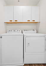 Washroom with cabinet space, separate washer and dryer, and light wood finished floors