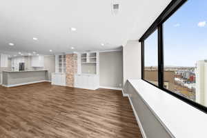 Unfurnished living room with dark wood-style floors, built in shelves, and recessed lighting