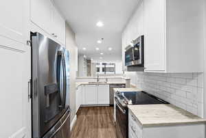 Kitchen featuring stainless steel appliances, white cabinets, recessed lighting, backsplash, and dark wood-type flooring