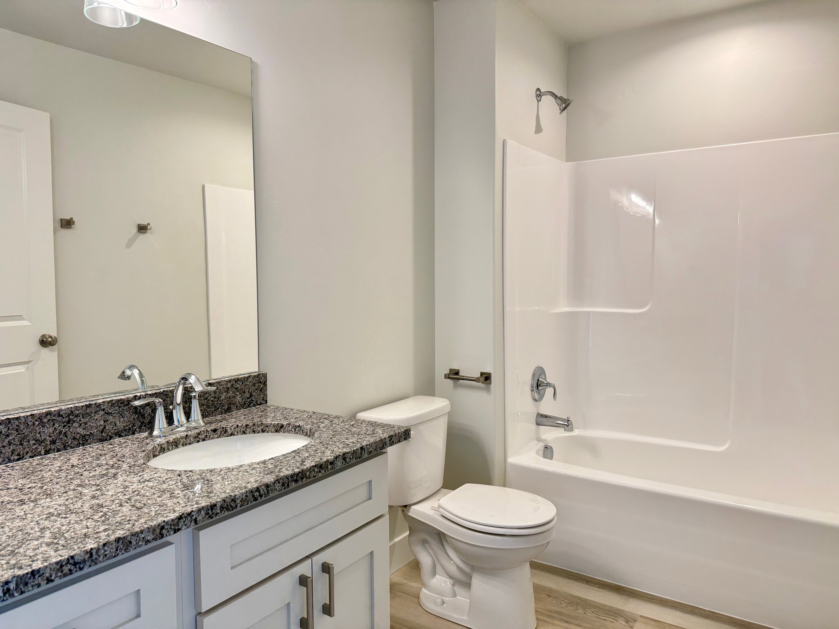 Full bathroom with shower / washtub combination, vanity, and light wood-type flooring