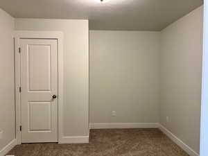 Carpeted spare room featuring baseboards and a textured ceiling