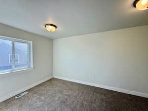 Empty room with carpet floors and a textured ceiling