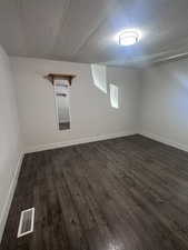 Finished below grade area featuring dark wood-style floors and baseboards