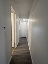 Corridor featuring baseboards and dark wood finished floors