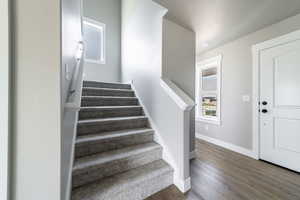 Staircase with wood finished floors and baseboards