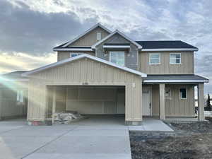 View of front facade featuring board and batten siding, a garage, driveway, and roof with shingles