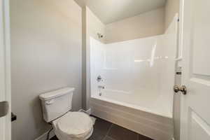 Full bathroom with dark tile patterned floors and shower / tub combination