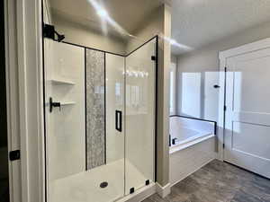 Full bath with a textured ceiling, a stall shower, a bath, and recessed lighting
