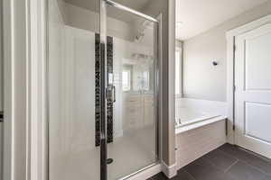 Full bathroom with dark tile patterned floors, a garden tub, a shower stall, and vanity