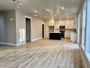 Kitchen featuring recessed lighting, open floor plan, white cabinetry, light countertops, and appliances with stainless steel finishes
