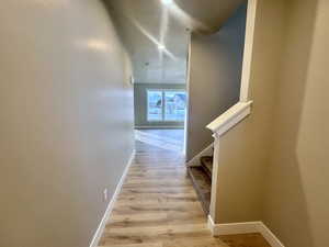 Hallway with light wood finished floors and stairway