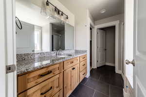 Full bathroom featuring vanity, dark tile patterned flooring, and a shower with curtain