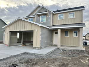 View of front of property with board and batten siding, a garage, and roof with shingles