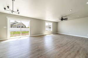 Unfurnished living room featuring a chandelier, a textured ceiling, wood finished floors, and recessed lighting