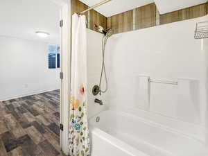 Bathroom featuring shower / bath combination with curtain and dark wood-style flooring