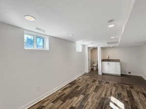 Below grade area with dark wood-style floors, recessed lighting, and a textured ceiling