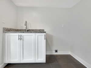Laundry room featuring baseboards and dark tile patterned flooring