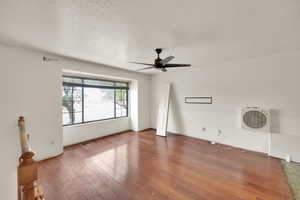 Empty room featuring a textured ceiling, hardwood / wood-style flooring, and ceiling fan