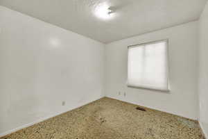 Unfurnished room featuring baseboards and a textured ceiling