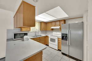 Kitchen with appliances with stainless steel finishes, light countertops, light tile patterned floors, and under cabinet range hood