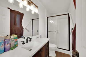 Full bath with vanity, a stall shower, and dark wood-style flooring